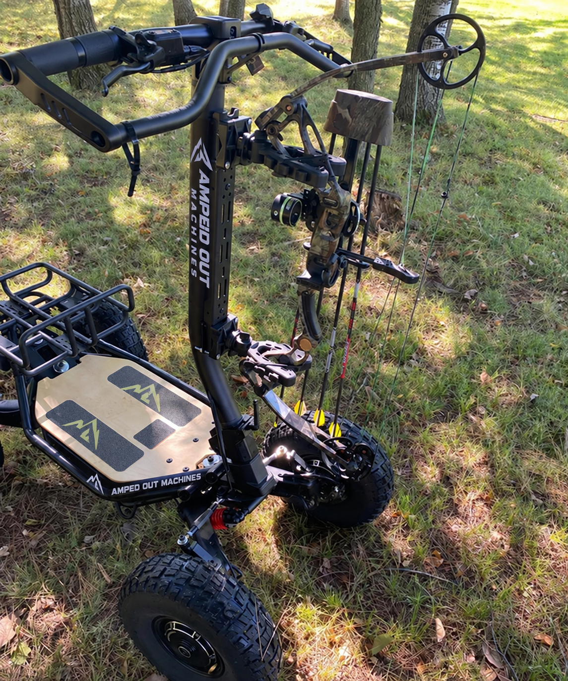 Amped Out Machines branded off-road electric hunting ATV with a mounted compound bow in a wooded setting